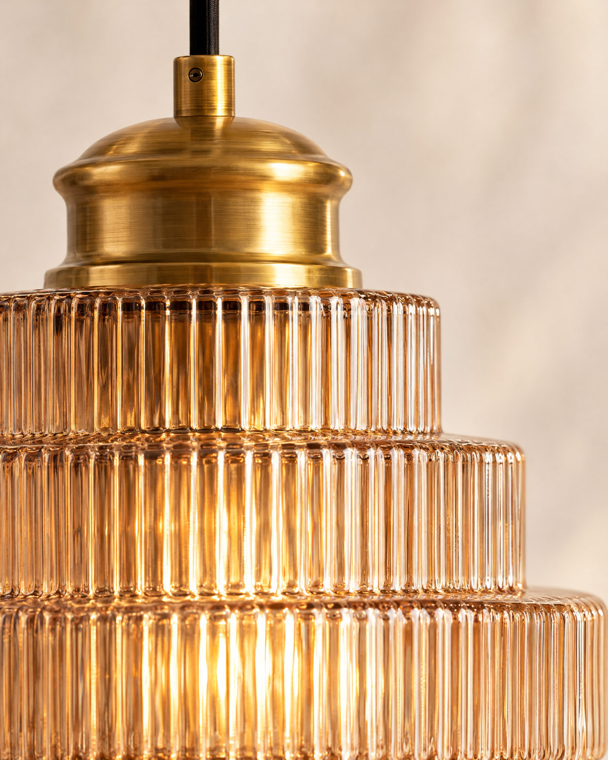 Close-up of the ribbed amber glass and brass cap, lit from within