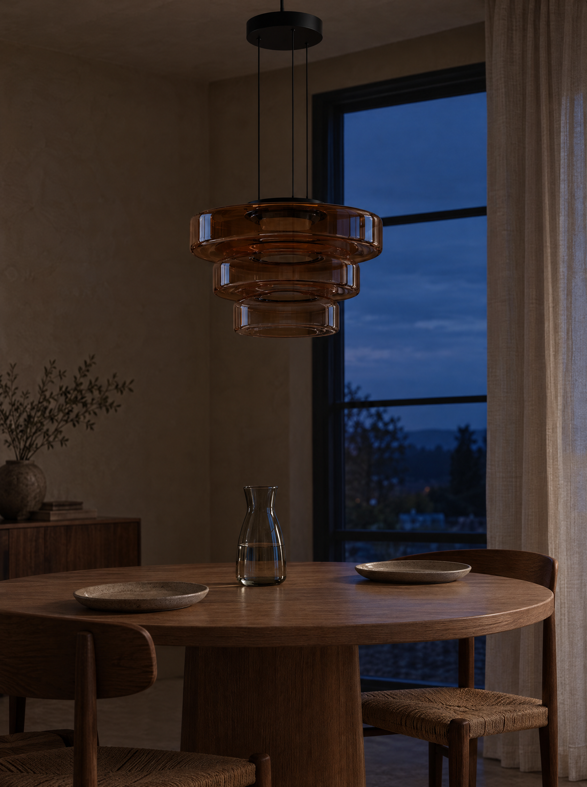 Three-layer amber glass pendant above a dining table at dusk, shown switched off and on